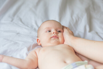 Happy infant girl doing baby massage by his mother at home. Newborn child about 5 months old