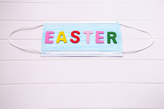 Inscription colorful decorated letters on blue disposable face mask. Happy Easter concept composition. Image with free copy space
