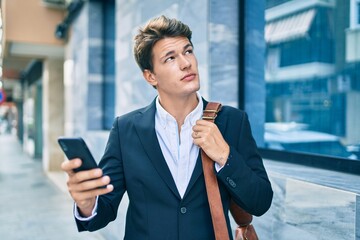 Young caucasian businessman with serious expression using smartphone at the city.