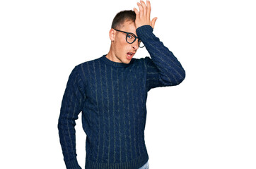Fototapeta premium Young blond man wearing casual clothes and glasses surprised with hand on head for mistake, remember error. forgot, bad memory concept.