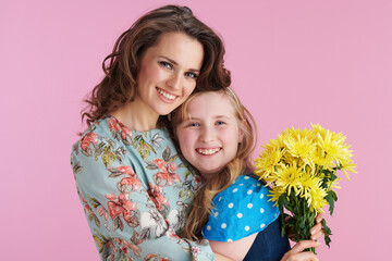 smiling elegant mother and daughter hugging on pink
