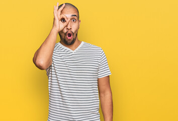Fototapeta na wymiar Hispanic adult man wearing casual clothes doing ok gesture shocked with surprised face, eye looking through fingers. unbelieving expression.