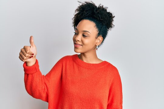 Young african american girl wearing casual clothes looking proud, smiling doing thumbs up gesture to the side