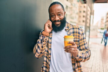 Handsome modern african american man with beard speaking on the phone at the city with a happy smile