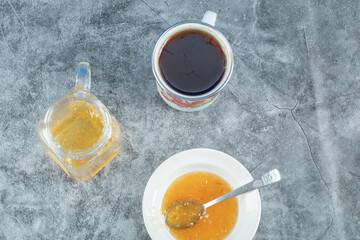 Peach jam with cup of tasty tea on a marble background