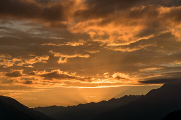 Aufgende Sonne über dem Goms bringt die Wolken zum Leuchten