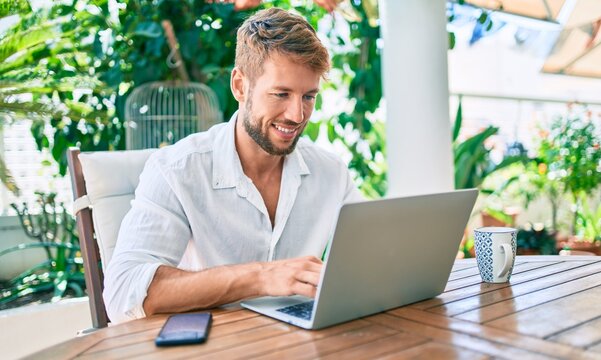 Handsome Caucasian Man Sitting On The Terrace Working From Home Using Computer Laptop