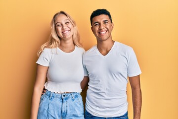 Young interracial couple wearing casual white tshirt with a happy and cool smile on face. lucky person.