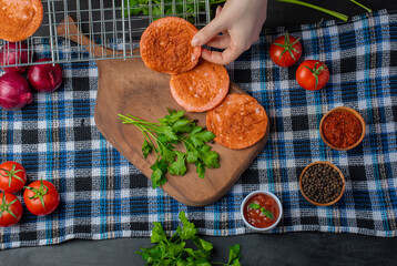Female hand putting grilled salami slice on wooden cutting table