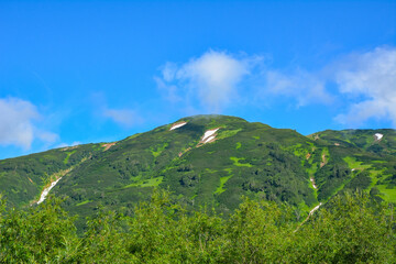 mountain landscape with blue sky and mountain covered with green vegetation. Kamchatka Russia