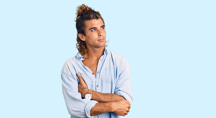 Young hispanic man wearing summer style looking to the side with arms crossed convinced and confident