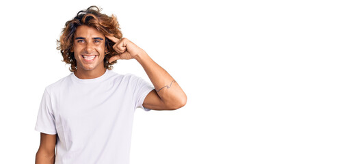 Young hispanic man wearing casual white tshirt smiling pointing to head with one finger, great idea or thought, good memory