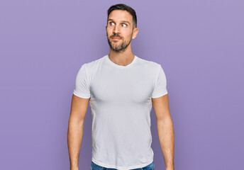 Handsome man with beard wearing casual white t shirt smiling looking to the side and staring away thinking.