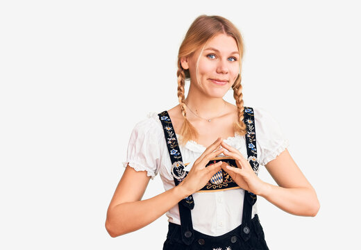 Young beautiful blonde woman wearing oktoberfest dress hands together and fingers crossed smiling relaxed and cheerful. success and optimistic