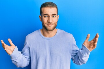 Fototapeta premium Young caucasian man wearing casual clothes clueless and confused with open arms, no idea and doubtful face.