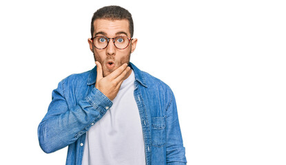 Young caucasian man wearing casual clothes looking fascinated with disbelief, surprise and amazed expression with hands on chin