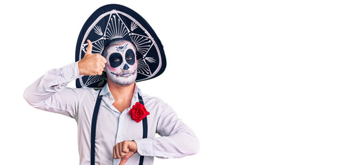 Man wearing day of the dead costume over background doing thumbs up and down, disagreement and agreement expression. crazy conflict