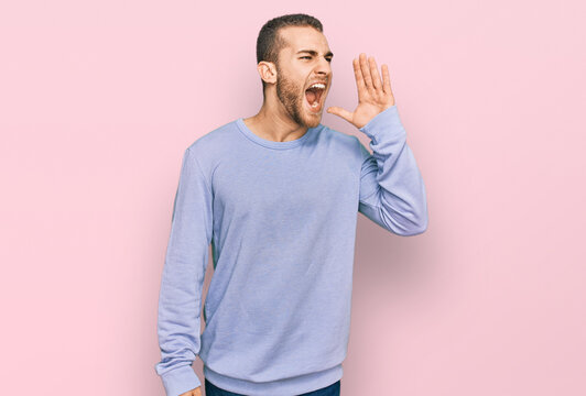 Young caucasian man wearing casual clothes shouting and screaming loud to side with hand on mouth. communication concept.