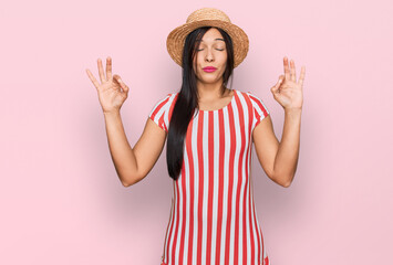 Young hispanic woman wearing summer hat relax and smiling with eyes closed doing meditation gesture with fingers. yoga concept.