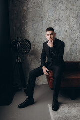 Wedding of a beautiful couple in a black dress, a bouquet of marsala color, at a festive table with candles and a cake against a black wall