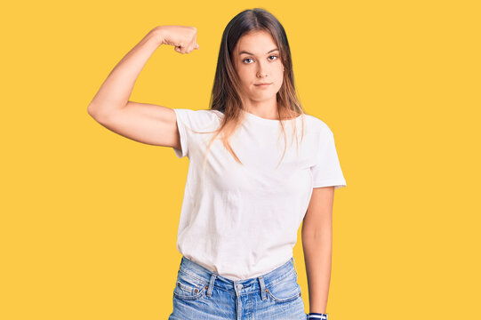 Beautiful caucasian woman wearing casual white tshirt strong person showing arm muscle, confident and proud of power