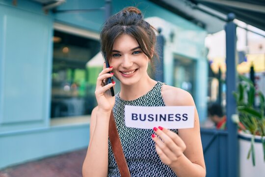 Young caucasian businesswoman talking on the smartphone and holding business word paper at the city.