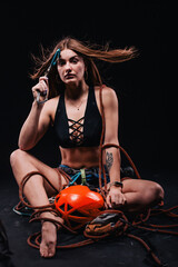 Fototapeta na wymiar A girl in climbing gear poses against a black background