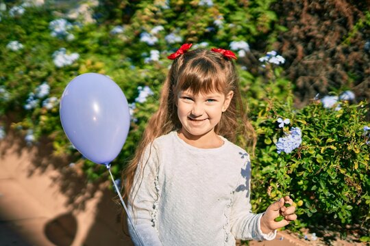 Adorable caucasian child girl  smiling happy playing with ballon at the park.