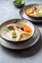 Traditional Jewish food dumplingd kreplach soup in gray bowl.