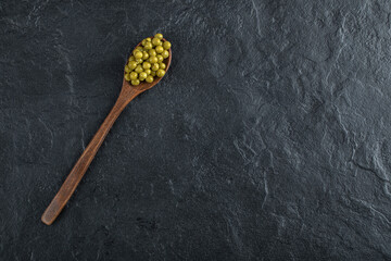 Canned olives with spoon over black background