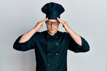 Handsome young man wearing professional cook uniform and hat with hand on head, headache because stress. suffering migraine.