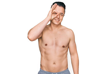 Fototapeta premium Handsome young man wearing swimwear shirtless doing ok gesture with hand smiling, eye looking through fingers with happy face.