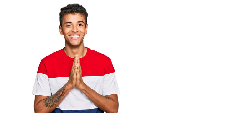 Young handsome african american man wearing casual clothes praying with hands together asking for forgiveness smiling confident.