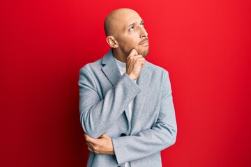 Bald man with beard wearing business jacket thinking concentrated about doubt with finger on chin and looking up wondering