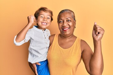 Hispanic grandson and grandmother together over yellow background screaming proud, celebrating...