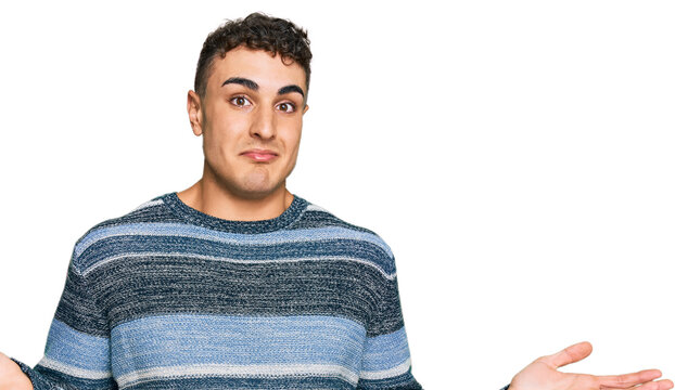 Hispanic young man wearing casual clothes clueless and confused expression with arms and hands raised. doubt concept.