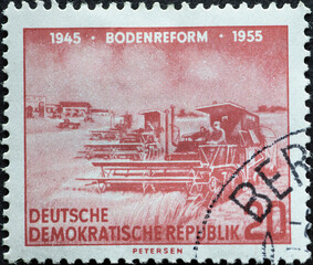GERMANY, DDR - CIRCA 1955 : a postage stamp from Germany, GDR showing a combine harvester in action in a cornfield Text: 10 years of land reform