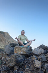 Naklejka na ściany i meble Man meditating on rock mountain