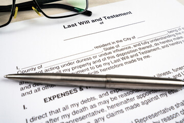Last will and testament document with pen and glasses on top.