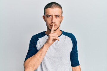 Hispanic young man wearing casual clothes asking to be quiet with finger on lips. silence and secret concept.