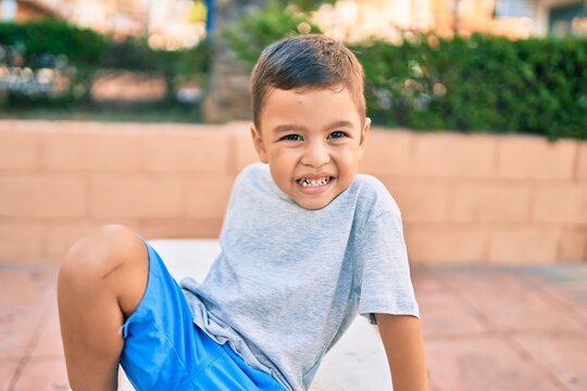 Adorable hispanic boy smiling happy sitting on the bench at the park.
