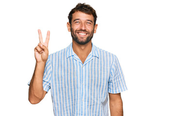 Handsome young man with beard wearing casual fresh shirt showing and pointing up with fingers number two while smiling confident and happy.