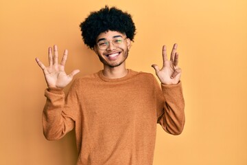 Young african american man with afro hair wearing casual winter sweater showing and pointing up...