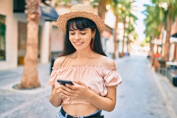 Young hispanic tourist girl wearing summer style using smartphone at the city.