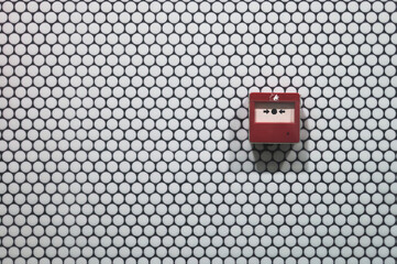 red fire button on a white round tile wall in a public space