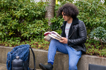 木の近くで本を読んでいる男・大学生
