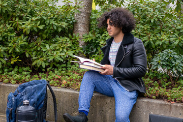 木の近くで本を読んでいる男・大学生