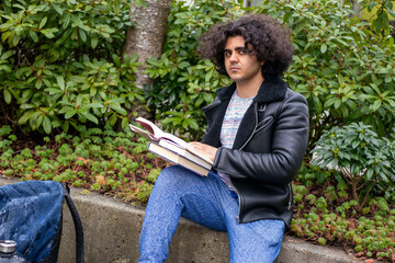 木の近くで本を読んでいる男・大学生