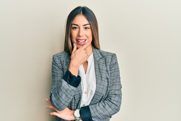 Young hispanic woman wearing business clothes looking confident at the camera smiling with crossed arms and hand raised on chin. thinking positive.