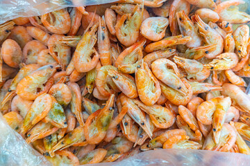 Pink fresh frozen shrimps with ice in a supermarket or fish shop. Fresh frozen prawns, delicacies, sea food concept. Uncooked seafood close up background